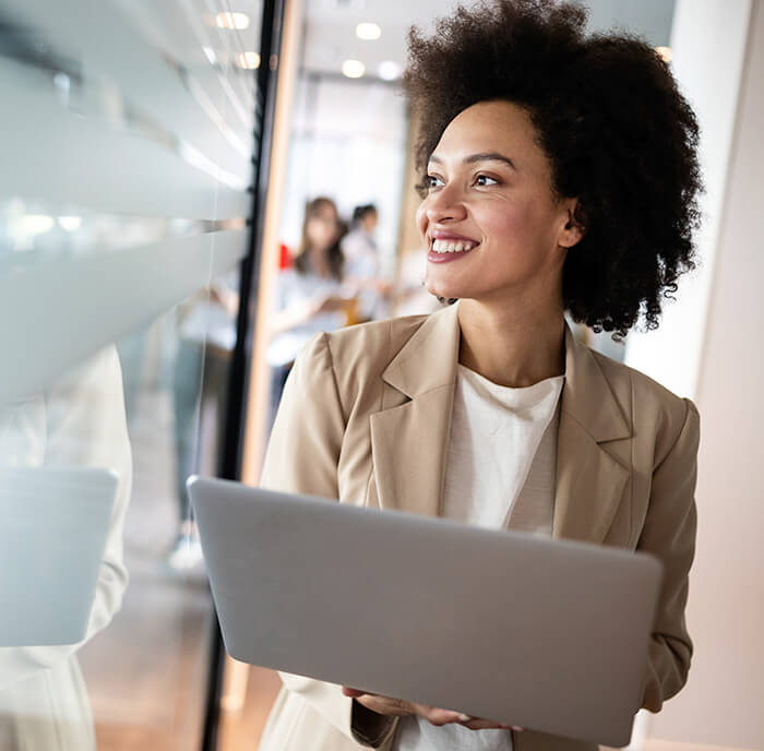 Femal mortgage professional carrying an open laptop in the office